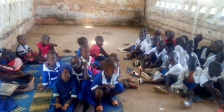 Tens of pupils at Kerewan Lower Basic School sit on the floor during lessons