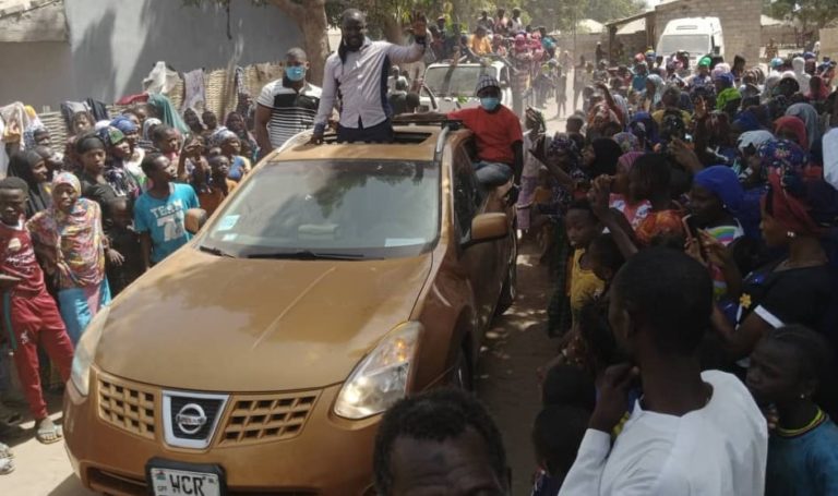 Large crowds receive Kitabu in Bissau and comedian responds by waving at them from roof of his car